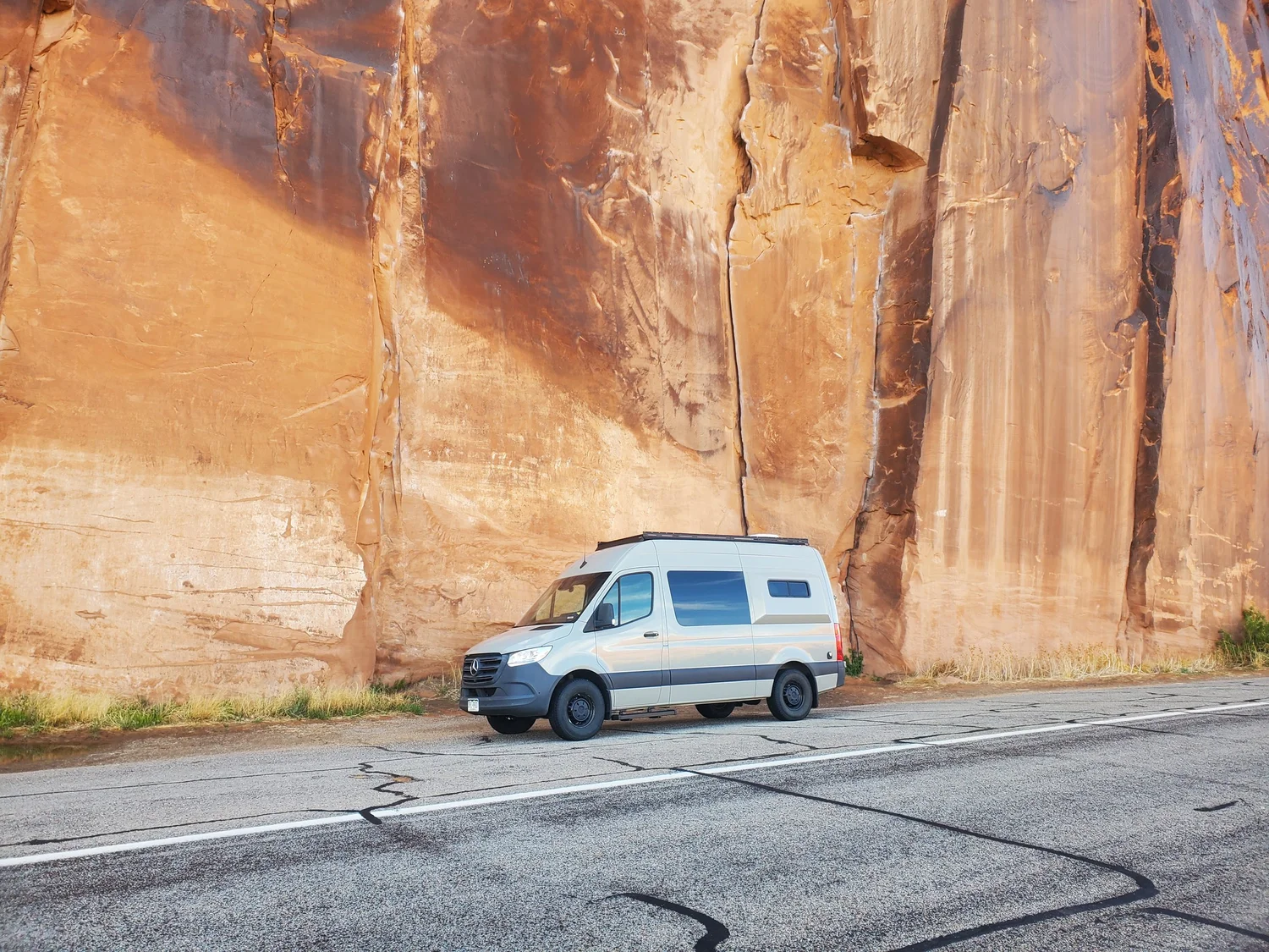 Nokhu van parked beneath towering sandstone canyon walls