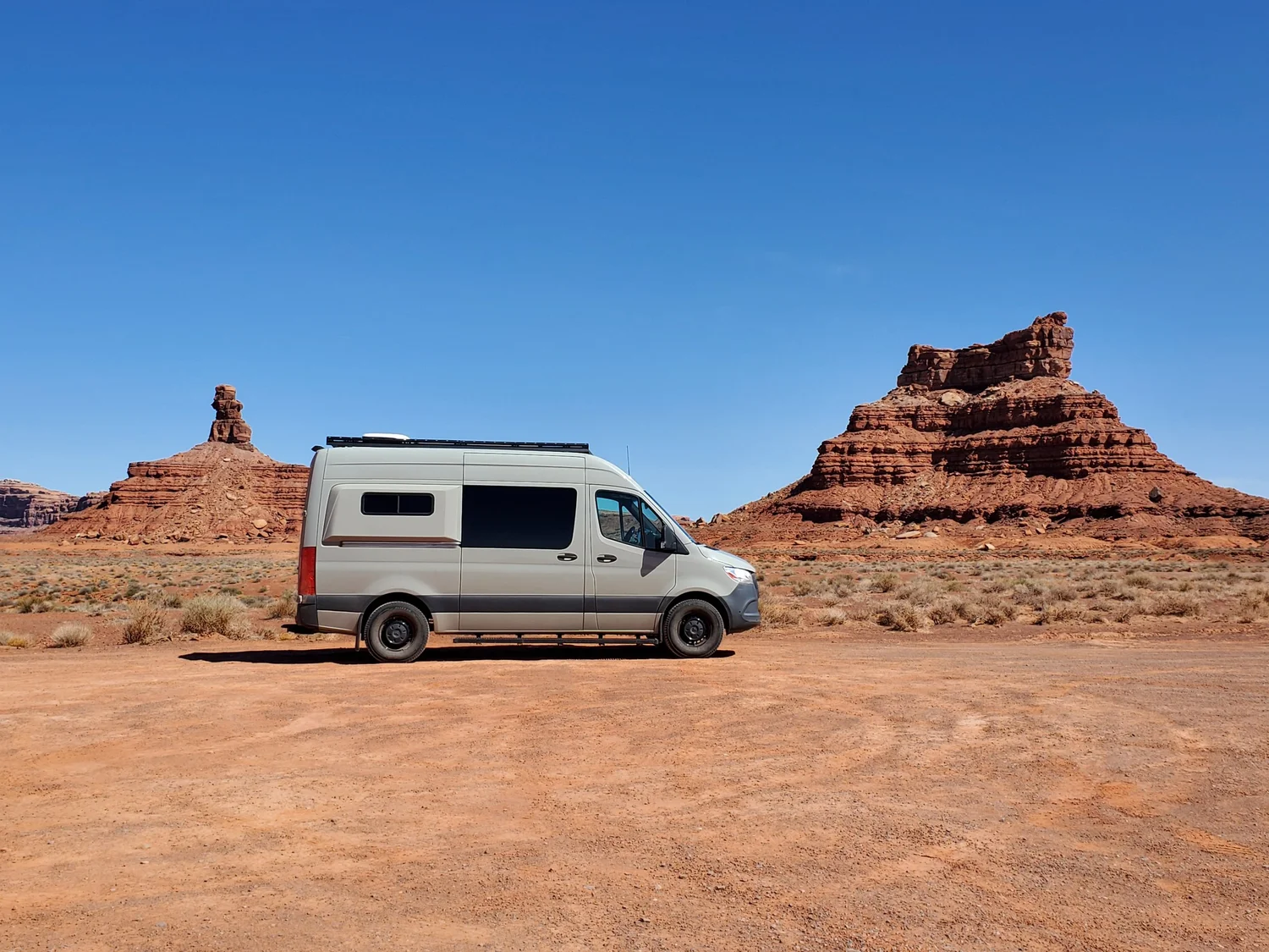 Nokhu van parked among red-rock desert buttes under a blue sky